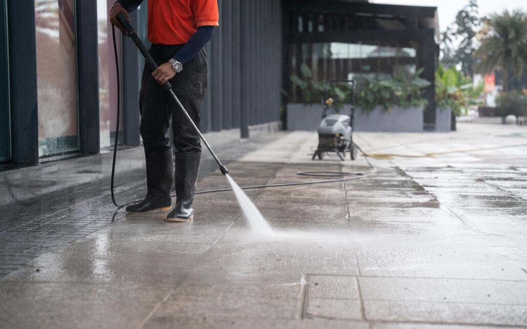 Person power washing sidewalk